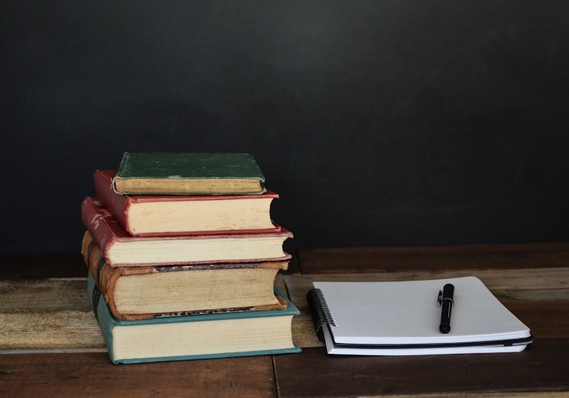 Hardback books stacked beside a notepad